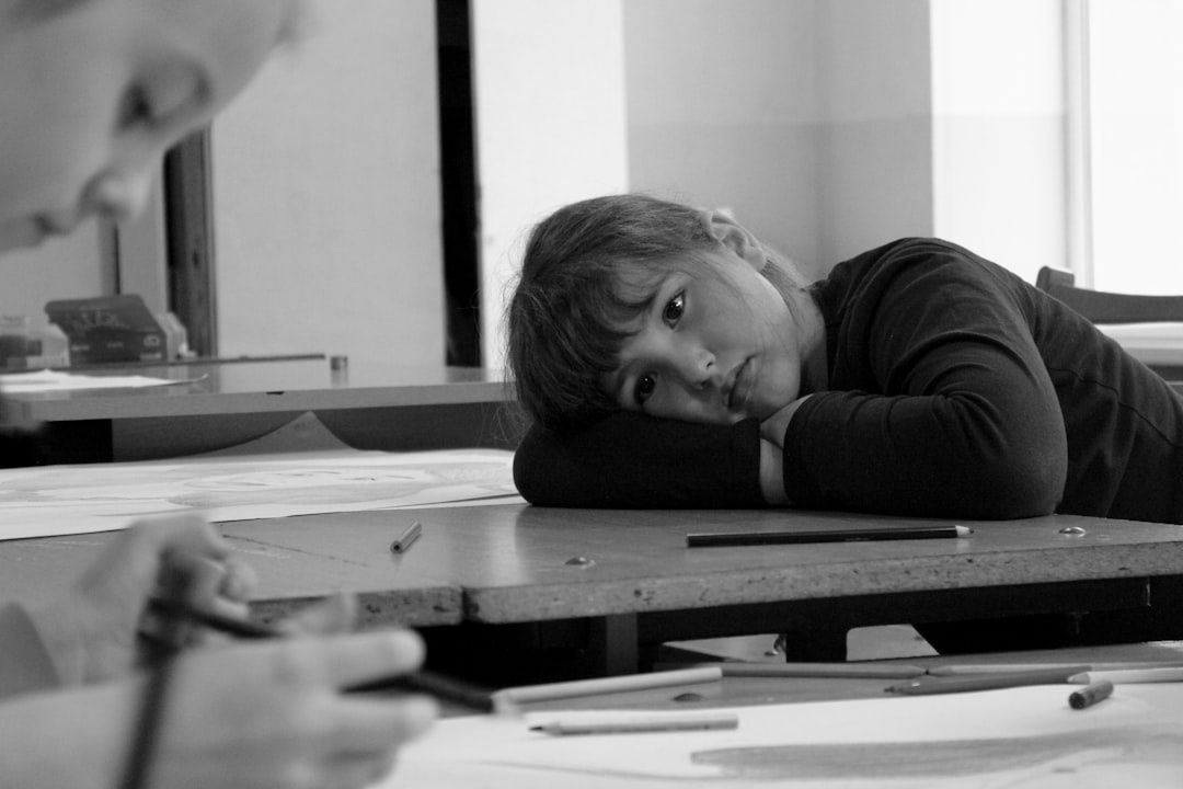 Élève appuyant sa tête sur son bras devant des dessins et crayons