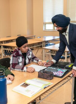 Un enseignant aide deux élèves à travailler en classe