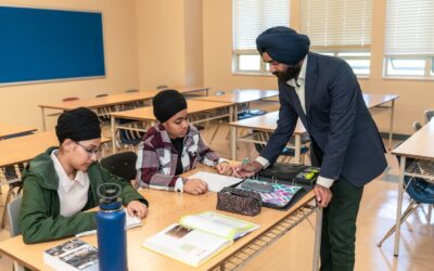 Un enseignant aide deux élèves à travailler en classe