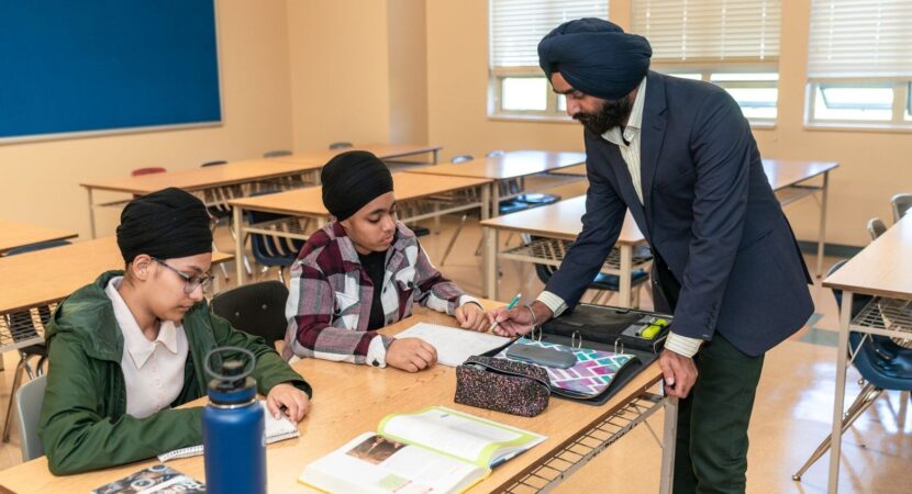 Un enseignant aide deux élèves à travailler en classe